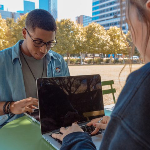 man and woman sitting while using MacBook Pro