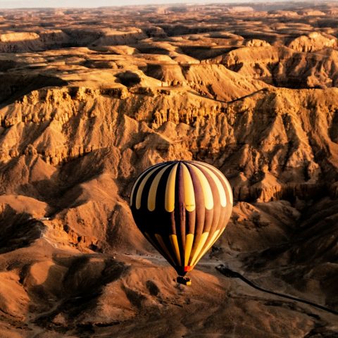 a hot air balloon flying over a desert landscape