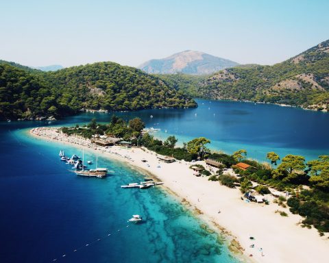 aerial photography of yachts on blue sea viewing mountain under blue and white skies during daytime