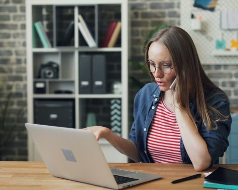 a woman sitting at a table using a laptop computer