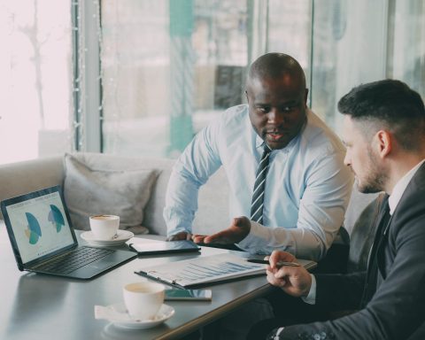 Two businessmen discussing charts on a laptop