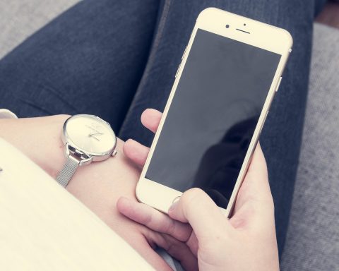 Persoon die 's avonds in een donkere kamer op een smartphone kijkt