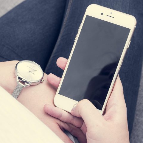 Persoon die 's avonds in een donkere kamer op een smartphone kijkt