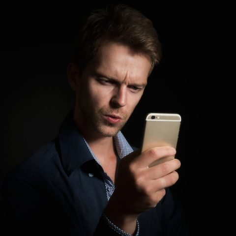 Persoon die nieuws leest op een smartphone, met meerdere apps zichtbaar op het scherm